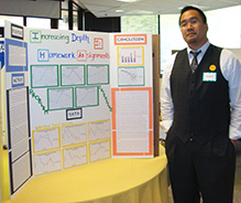 A research student in front of his poster presentation