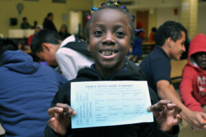 A smiling young girl holding up a certificate